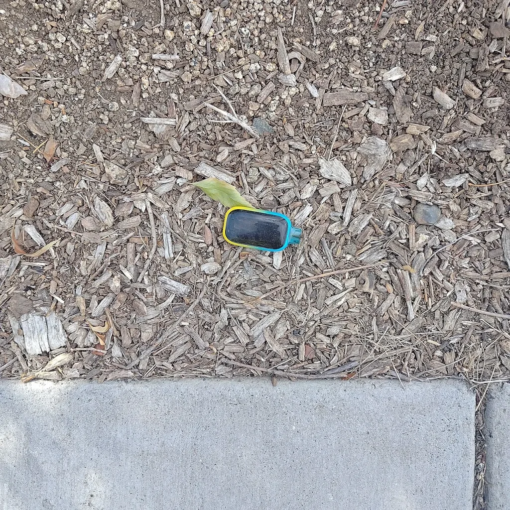 Disposable Vapes: The Pocket Habit Leaving Plastic and Batteries on Our Streets A discarded disposable vape lying on bark mulch beside a pavement